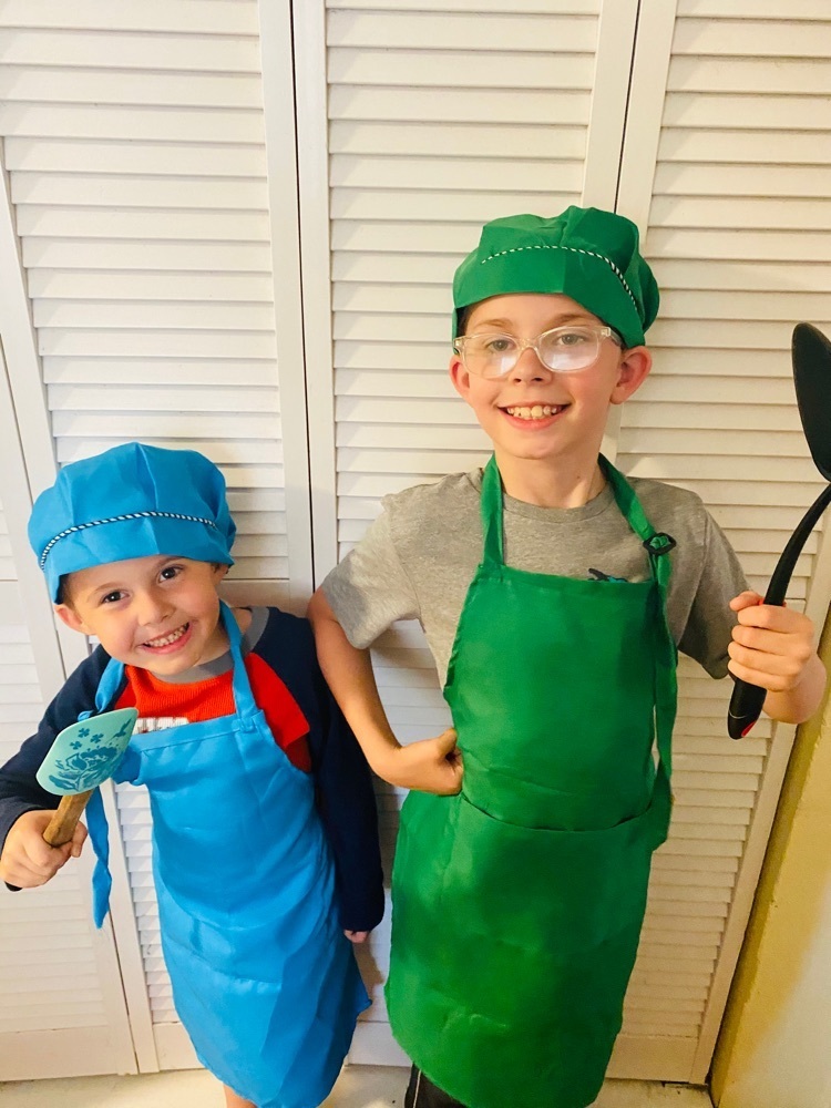 two boys dressed in aprons and chef hats